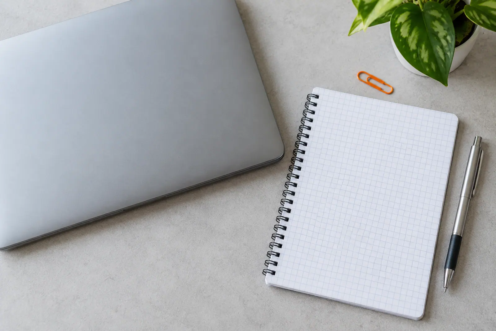 Laptop zamknięty, obok notes i długopis